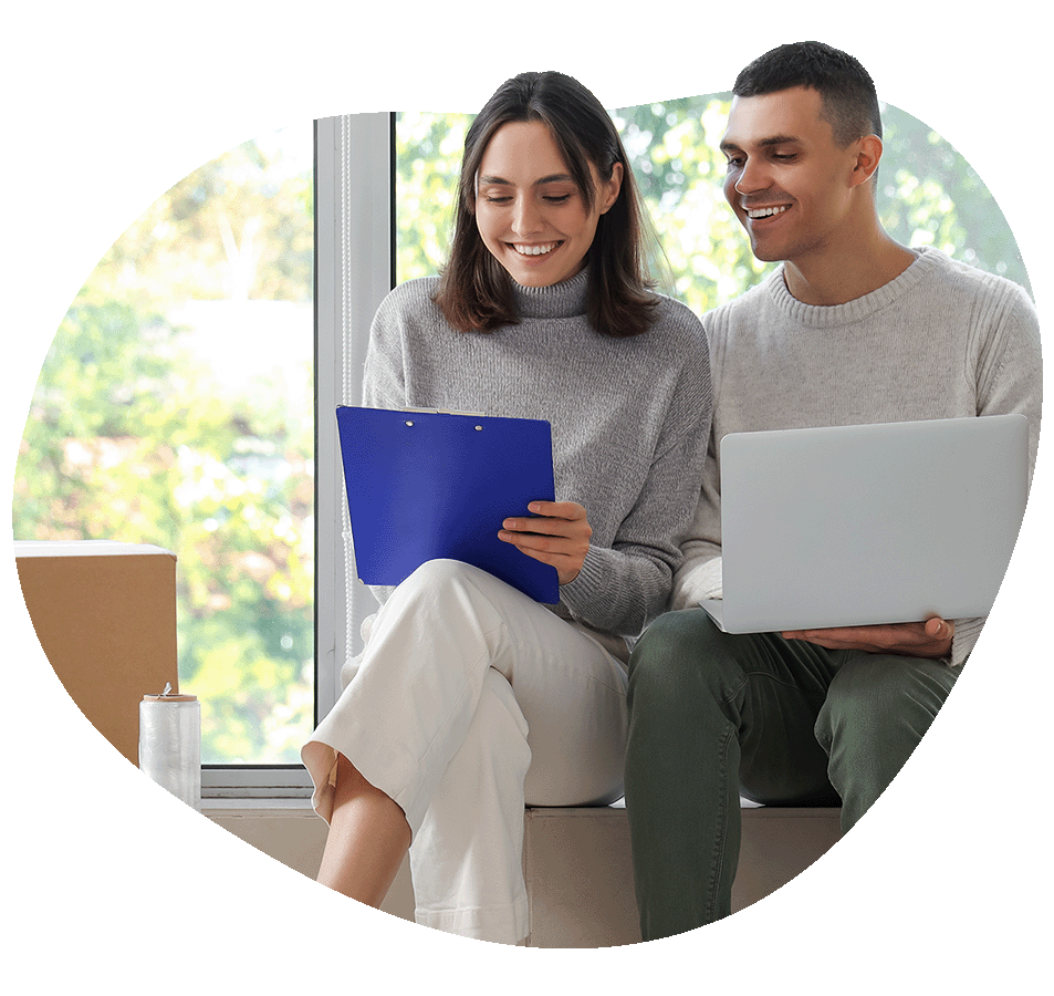 Couple sitting on moving box looking at clip board