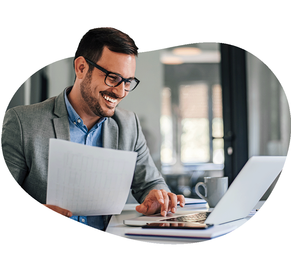 Man holding papers and looking at laptop